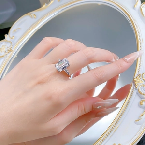 Detail of emerald cut gemstone ring with baguette side stones on a mirror surface