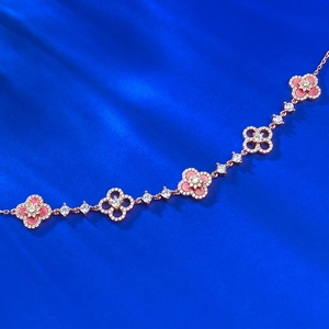 Rose gold clover necklace with pink enamel and sparkling crystals on blue silk
