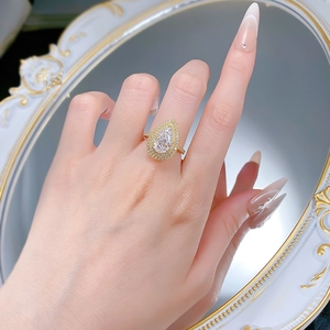 Detailed view of pear-shaped halo ring featuring white gemstones and gold plated band