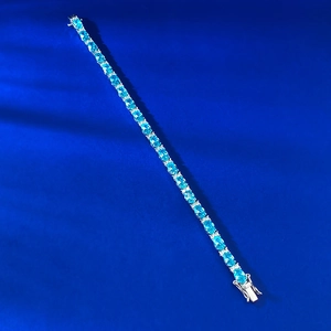Detail of silver tennis bracelet featuring oval blue gemstones and pavé set accents