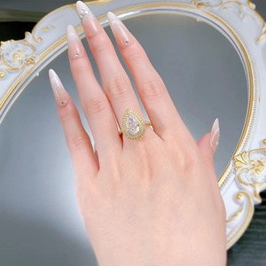 Detailed close-up of a pear-cut gold ring featuring a double diamond halo on a finger