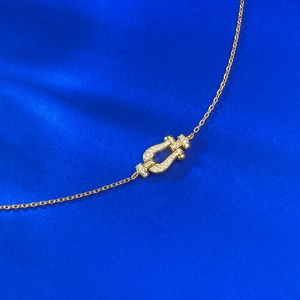 Detail view of gold horseshoe buckle bracelet with pavé cubic zirconia on blue silk