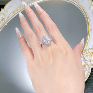 Close-up of pear-cut sparkling ring with double halo setting on a model finger