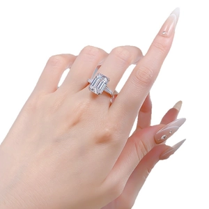 Emerald cut solitaire ring with side stones in silver on a model's hand