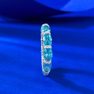 Macro side view of S925 silver full eternity ring with oval blue stones and small diamonds