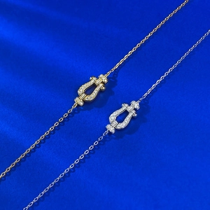 Detailed close-up of gold and silver horseshoe pendants with pavé diamonds on blue texture
