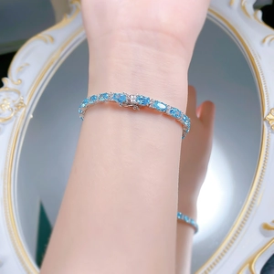 Close-up of S925 silver bracelet with blue oval gems and diamond accents on a mirror