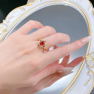 Détail d'une bague dorée vintage avec rubis rouge ovale portée sur une main féminine
