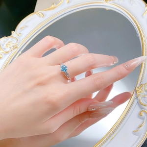 Detailed view of floral silver ring with round blue gemstone on a decorative mirror