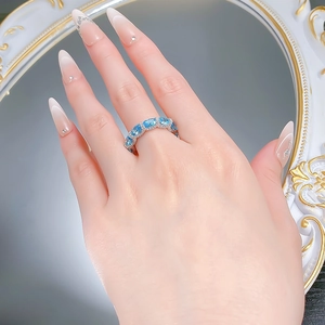 Detail of S925 silver ring with oval aquamarine stones and diamond halo on finger