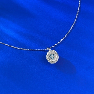 Macro detail of S925 silver necklace with hollow floral pattern and blue gemstone pendant