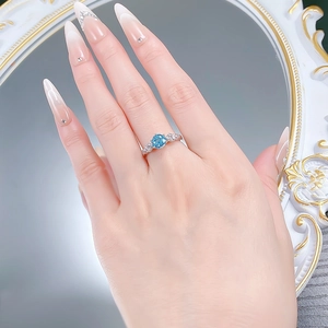Detailed view of aquamarine-colored ring with vintage engraved band on model finger