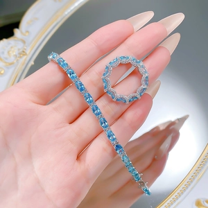 Close-up of S925 silver tennis bracelet and ring set with oval blue gemstones