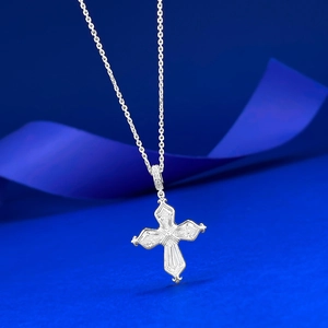 Macro view of S925 silver iris cross pendant with gems on blue textured background