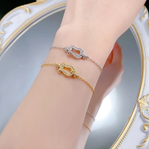 Macro detail of silver and gold horseshoe buckle bracelets with pavé setting and O-chain