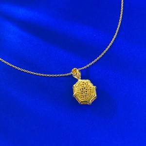Detailed close-up of the geometric cutout flower pattern on the golden pendant back