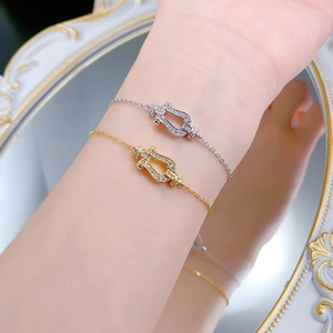 Close-up of gold and silver horseshoe bracelets with pavé diamonds on a model wrist