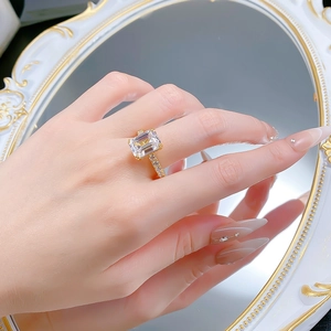 Close-up of gold S925 silver ring with rectangular radiant cut diamond on mirror surface