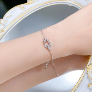 Macro shot of silver horseshoe clasp bracelet with cubic zirconia on model's wrist