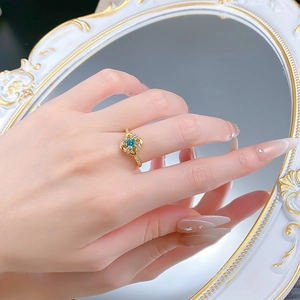 Gros plan d'une bague en argent S925 avec pierre cyan et halo de diamants au doigt