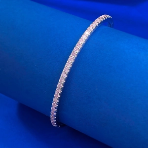 Minimalist S925 sterling silver bangle featuring pink crystals on a blue display stand