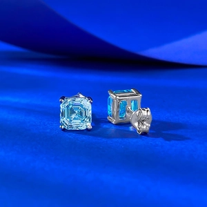Macro detail of emerald-cut blue gemstone earrings with four-prong silver setting