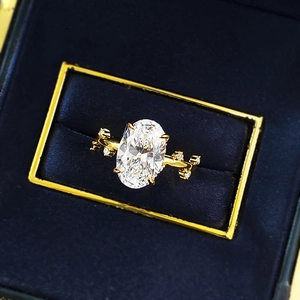 Bague de fiançailles dorée à coupe ovale avec motif de branche dans une boîte bleue