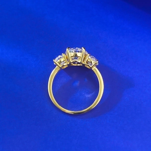 Macro shot of three-stone gold engagement ring with oval and round cut gemstones