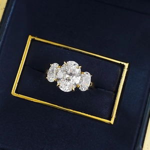 Elegant three-stone ring with oval-cut diamonds on a luxury blue velvet jewelry box