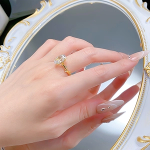 Gros plan sur bague cristal ovale avec détails feuilles dorées reflétés dans un miroir