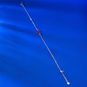 Détail d'un bracelet ajustable en argent avec une pierre précieuse en forme de cœur rouge