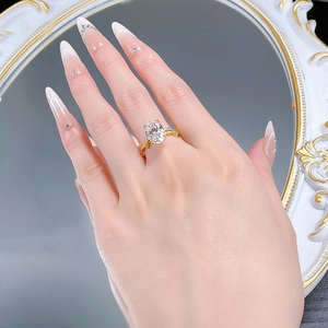 Vue détaillée d'une bague avec pierre ovale et anneau doré portée sur la main