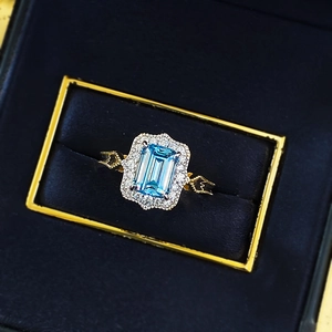 Classic S925 silver ring with emerald-cut blue gemstone and halo stones in a velvet box