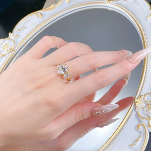 Close-up of golden three-stone ring with oval-cut crystals worn in a vintage mirror setting