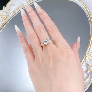 Close-up of a three-stone oval cut diamond ring on a hand with a golden band finish