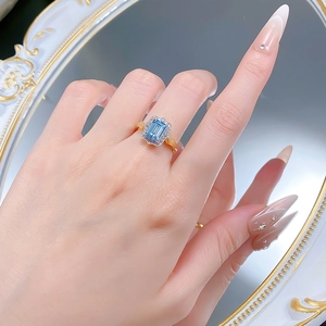 Macro view of a 925 silver ring featuring a halo-set blue gemstone on a finger