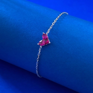 Bracelet en argent S925 avec double cœur en rubis rouge sur support de bijoux bleu