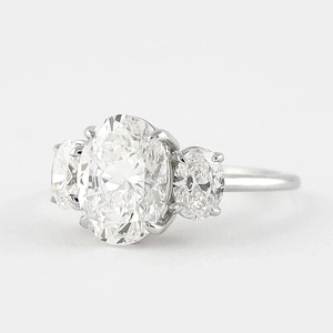 Macro side view of an oval-cut three-stone diamond ring with classic prong setting