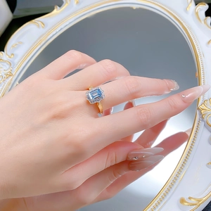 Close-up of sky blue rectangle ring with halo diamonds and vintage gold floral texture