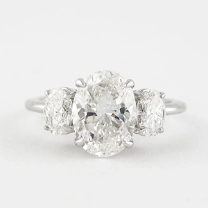 Macro shot of silver three-stone oval-cut diamond engagement ring with claw setting