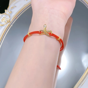 Detail of red cord bracelet with gold plated snake charm and micro-pave crystals