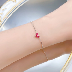 Détail d'un bracelet en argent S925 avec trois zircons rouges en forme de cœur