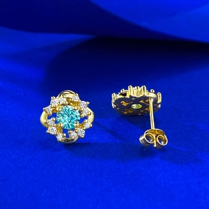 Detail showing flower-shaped S925 silver earrings with blue stone and gold finish