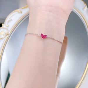 Détail d'un bracelet en argent S925 avec une gemme coeur rouge sur le poignet