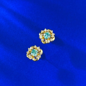 Macro shot of S925 silver flower stud earrings with cyan gemstones and small diamonds