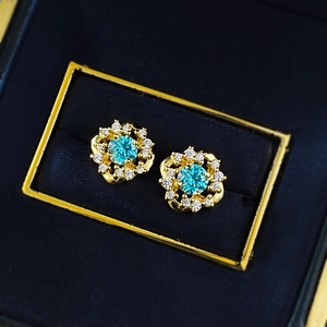 Elegant gold flower stud earrings featuring blue gems and diamonds in a velvet box