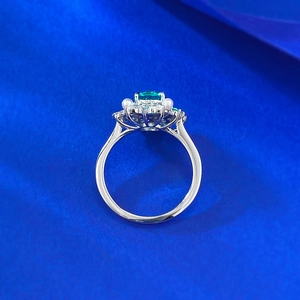 Macro shot of silver ring with green oval gemstone surrounded by pearls and small diamonds