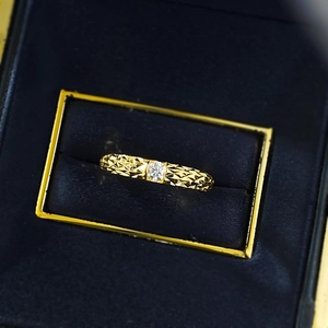 Macro shot of gold ring with ice-crushed dragon scale texture and a central moissanite