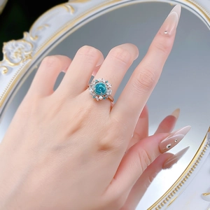Detail of Paraiba blue gemstone ring with pearls and floral diamond accents on finger