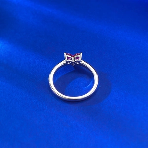 Macro view of 925 silver ring featuring butterfly shaped red gemstones on blue fabric